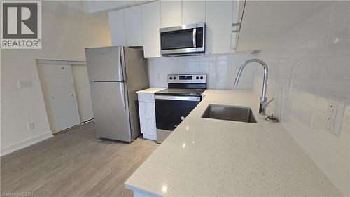 Contemporary kitchen featuring a stainless steel appliance suite, white cabinetry, quartz countertops, a single-basin sink with a gooseneck faucet, and a white subway tile backsplash - 16 Melbourne Avenue Unit# 210B, St. Catharines, ON - Indoor Photo Showing Kitchen With Stainless Steel Kitchen With Upgraded Kitchen
