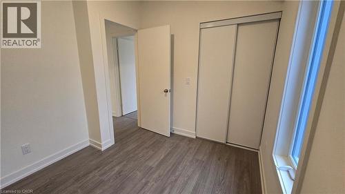 Interior room featuring wood-finish flooring, light-toned walls, and a white interior door - 16 Melbourne Avenue Unit# 210B, St. Catharines, ON - Indoor Photo Showing Other Room