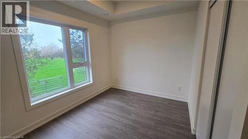 Room featuring a large window, dark wood-finish flooring, white baseboards, and a built-in sliding door closet - 16 Melbourne Avenue Unit# 210B, St. Catharines, ON - Indoor Photo Showing Other Room