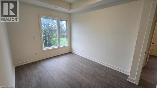 Room featuring a large picture window, wood-finish flooring, white walls, recessed ceiling lighting, and crisp white baseboards - 16 Melbourne Avenue Unit# 210B, St. Catharines, ON - Indoor Photo Showing Other Room