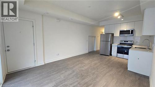 Open concept living space featuring wood-finish flooring - 16 Melbourne Avenue Unit# 210B, St. Catharines, ON - Indoor Photo Showing Kitchen With Stainless Steel Kitchen