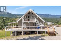 Back of the house showing the wrap around deck plus a great little spot for morning coffee or evening glass of wine of the primary suite. - 