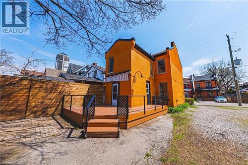 Exterior featuring an expansive wood-finish deck with steps, black railings, and a white and orange striped awning - 116 Catharine Street S, Hamilton, ON - Outdoor