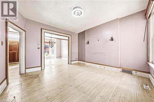 Spacious room featuring wood-finish flooring, white baseboards, and a semi-flush mount ceiling fixture - 116 Catharine Street S, Hamilton, ON - Indoor Photo Showing Other Room