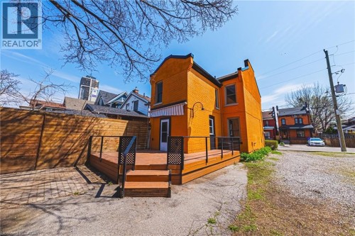 Exterior featuring an expansive wood-finish deck with steps, black railings, and a white and orange striped awning - 116 Catharine Street S, Hamilton, ON - Outdoor