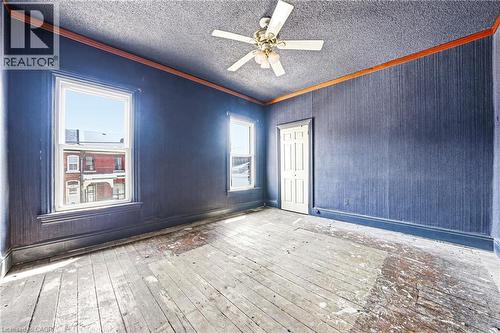 Room featuring two windows, a ceiling fan with light fixture, paneled door, and wood-finish flooring - 116 Catharine Street S, Hamilton, ON - Indoor Photo Showing Other Room