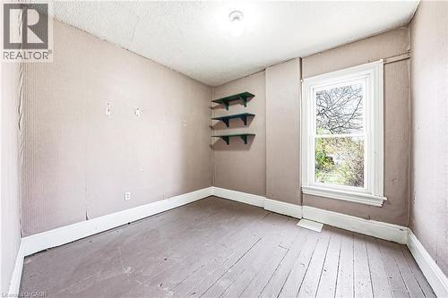 Room featuring a window with white trim, wood-finish flooring, and built-in shelving - 116 Catharine Street S, Hamilton, ON - Indoor Photo Showing Other Room