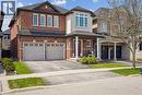 Brick facade residence featuring a two-car garage, multiple large windows, a covered front porch with white columns, and an integrated bay window element - 4679 Webb Street, Burlington, ON  - Outdoor With Facade 