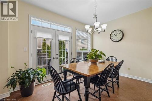 Dining area featuring ceramic tile flooring, a multi-pane glass double door with transom, and a five-light chandelier - 4679 Webb Street, Burlington, ON - Indoor Photo Showing Dining Room