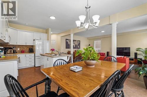 Open-concept living area featuring a kitchen with white cabinetry, a center island with a sink, and a tiled backsplash - 4679 Webb Street, Burlington, ON - Indoor Photo Showing Dining Room