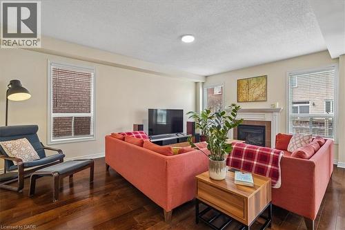 Spacious living area featuring rich wood-finish flooring, a classic fireplace with a white mantel, and multiple windows with blinds - 4679 Webb Street, Burlington, ON - Indoor Photo Showing Living Room With Fireplace
