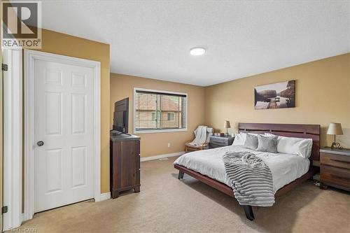 Carpeted bedroom featuring a window with horizontal blinds, a white six-panel door, and a flush-mount ceiling light fixture - 4679 Webb Street, Burlington, ON - Indoor Photo Showing Bedroom