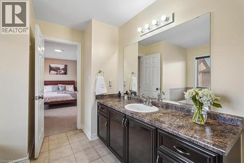 Bathroom vanity featuring a single basin sink set in a patterned countertop, with dark wood-finish cabinetry and a large wall-mounted mirror - 4679 Webb Street, Burlington, ON - Indoor Photo Showing Bathroom