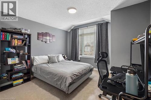 Carpeted room featuring a window with blinds, a ceiling-mounted light fixture, and a built-in shelving unit - 4679 Webb Street, Burlington, ON - Indoor Photo Showing Bedroom