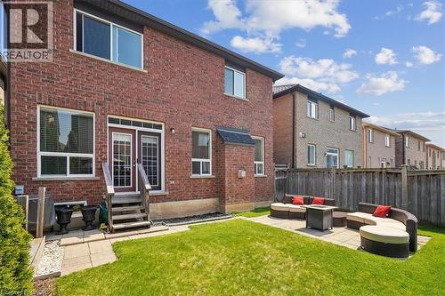 Brick exterior featuring multiple windows and a wood staircase leading to double French doors - 4679 Webb Street, Burlington, ON - Outdoor With Exterior