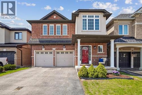 Brick and stucco exterior featuring a covered front porch with white pillars, a red entry door, and a second-story bay window - 4679 Webb Street, Burlington, ON - Outdoor With Facade