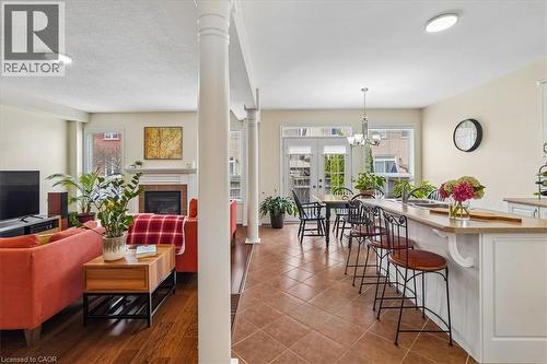 Open-concept kitchen and living area featuring ceramic tile flooring, a kitchen island with seating, white cabinetry, and a fireplace with a mantel - 4679 Webb Street, Burlington, ON - Indoor With Fireplace