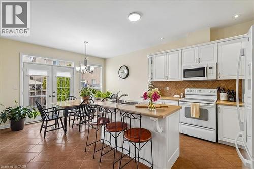 Kitchen featuring white cabinetry, brown tile backsplash, light countertops, and an integrated kitchen island with seating - 4679 Webb Street, Burlington, ON - Indoor Photo Showing Kitchen With Double Sink