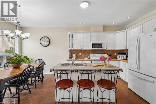 Kitchen featuring white cabinetry, integrated appliances, and a central island with a double basin sink - 4679 Webb Street, Burlington, ON - Indoor
