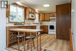 Kitchen featuring wood cabinetry, laminate countertops, and wood-finish flooring - 