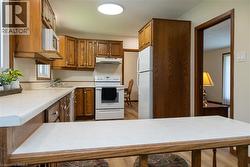 Kitchen featuring wood cabinetry, white countertops, and white appliances including a refrigerator, range, and microwave - 