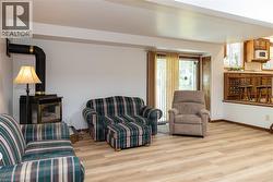 Spacious room featuring wood-finish flooring, a freestanding stove with a black pipe, and white walls - 