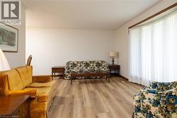 Bright interior space featuring light wood-finish flooring, white walls, and a large bay window with white vertical blinds - 