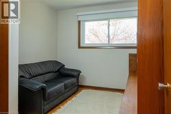 Hardwood flooring with a light area rug, white walls, and a window featuring wood trim - 