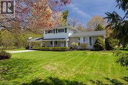 Split-level home featuring a brick and white siding exterior, dark gray roof, and green window shutters - 