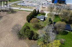 Aerial perspective showcasing a single-family residence with a dark gray roof, surrounded by mature trees and green lawn space - 