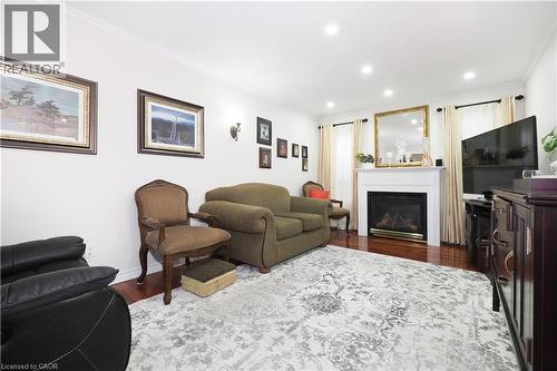 Living area with dark wood-style flooring, a glass covered fireplace, crown molding, and recessed lighting - 89 Lynnhaven Court, Kitchener, ON - Indoor Photo Showing Living Room With Fireplace