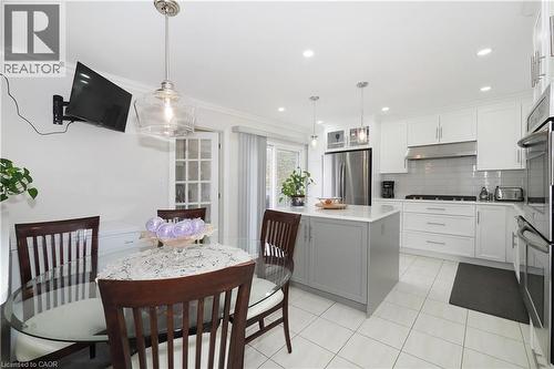 Kitchen featuring dual tone cabinetry, stainless steel appliances, a center island, backsplash, and decorative light fixtures - 89 Lynnhaven Court, Kitchener, ON - Indoor Photo Showing Dining Room