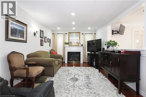 Living area with crown molding, a glass covered fireplace, dark wood finished floors, and recessed lighting - 89 Lynnhaven Court, Kitchener, ON - Indoor Photo Showing Living Room With Fireplace