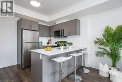 Modern kitchen featuring grey cabinetry, stainless steel appliances, a white subway tile backsplash - 
