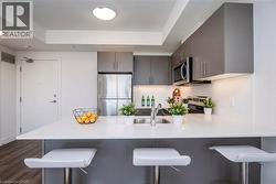 Kitchen featuring a center island with a sink, white countertop, and dark grey cabinetry - 