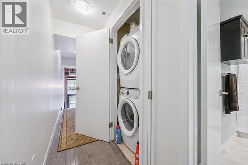 Laundry area with light wood-style floors and stacked washer and clothes dryer - 85 Spruce Street Unit# 106, Cambridge, ON - Indoor Photo Showing Laundry Room