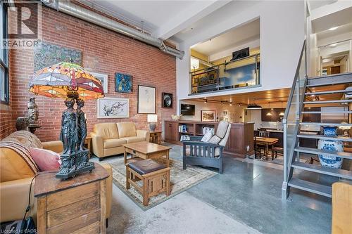 Living area featuring concrete flooring, a high ceiling, and brick wall - 85 Spruce Street Unit# 106, Cambridge, ON - Indoor