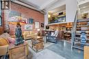 Living area featuring concrete flooring, a high ceiling, and brick wall - 85 Spruce Street Unit# 106, Cambridge, ON  - Indoor 