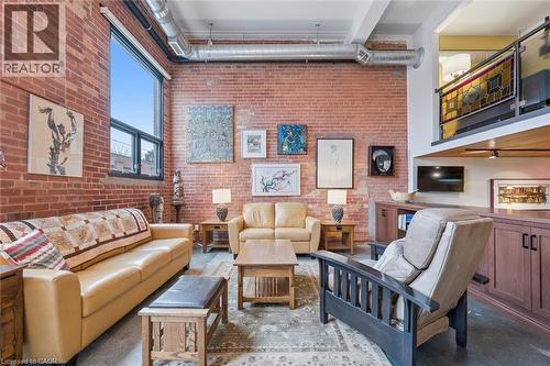 Living room featuring a high ceiling and brick wall - 85 Spruce Street Unit# 106, Cambridge, ON - Indoor