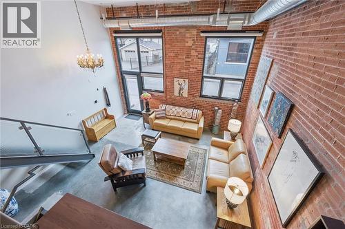 Living area featuring concrete floors, a high ceiling, brick wall, and a chandelier - 85 Spruce Street Unit# 106, Cambridge, ON -  With Exterior