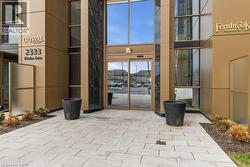 Building entrance featuring automatic glass doors, reflective bronze-toned paneling, and dark marble-look accents - 