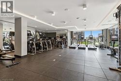 Fitness center featuring dark rubber flooring, floor-to-ceiling windows, mirrored walls, recessed lighting, and a selection of cardio equipment - 