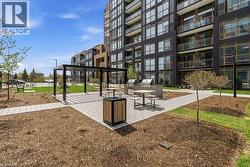 Outdoor entertaining area featuring a dark metal pergola, paver patio, two built-in grilling stations, and a putting green - 