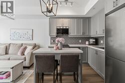 Open-concept kitchen featuring grey shaker-style cabinetry, stainless steel appliances, and a grey subway tile backsplash - 