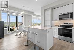 Kitchen with stainless steel appliances, white cabinetry, backsplash, a breakfast bar, and light wood-style floors - 