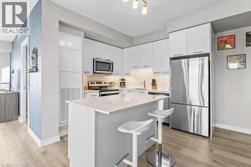 Kitchen featuring stainless steel appliances, white cabinetry, tasteful backsplash, a center island, and light wood-type flooring - 385 Winston Road Unit# 1402, Grimsby, ON - Indoor Photo Showing Kitchen With Upgraded Kitchen