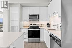 Kitchen featuring stainless steel appliances, light stone counters, white cabinetry, tasteful backsplash, and light wood finished floors - 