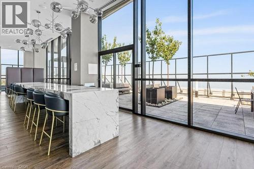 Kitchen with expansive windows, light wood-style floors, a water view, decorative light fixtures, and light stone counters - 385 Winston Road Unit# 1402, Grimsby, ON - Indoor