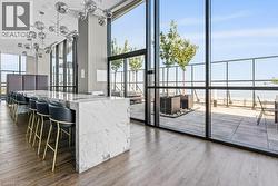 Kitchen with expansive windows, light wood-style floors, a water view, decorative light fixtures, and light stone counters - 