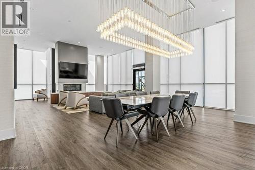 Dining room with dark wood finished floors, a chandelier, and a glass covered fireplace - 385 Winston Road Unit# 1402, Grimsby, ON - Indoor